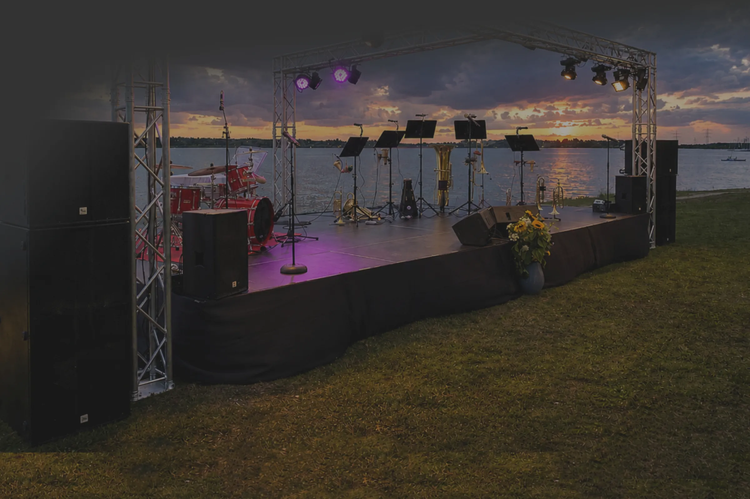 Open-Air-Bühnenpodest mit Layher-Gerüstunterbau, Traversen und Instrumenten am See