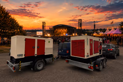 Zwei Stromaggregate auf Anhängern vor einer Open-Air-Bühne