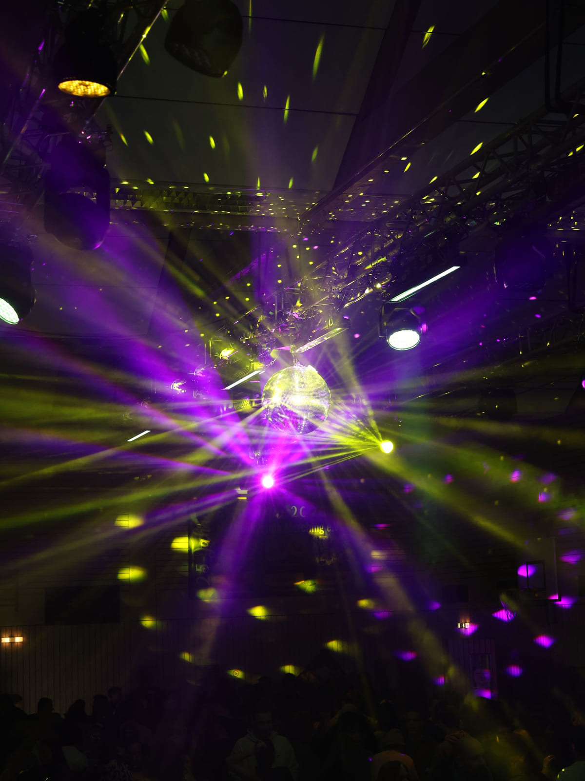 Discokugel mit violetten und gelben Lichtstrahlen an der Decke