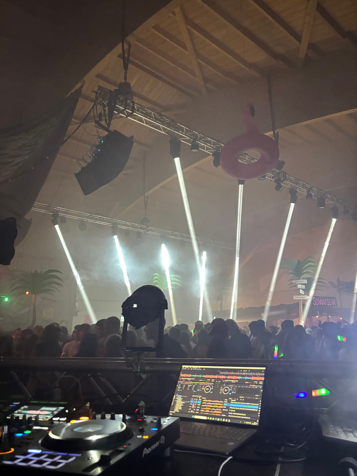 Blick vom DJ-Pult auf Lichtstrahlen, Publikum und hängenden Flamingo