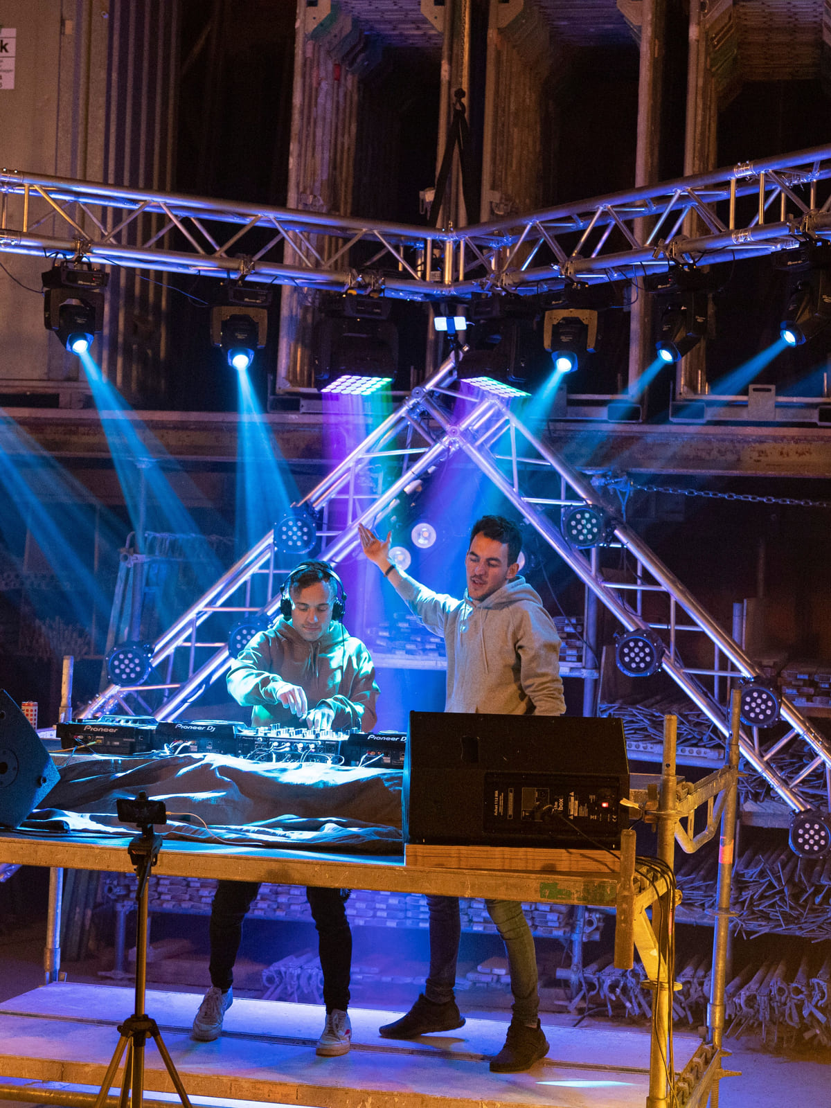 Zwei DJs auf einem Podest unter blauen Lichtstrahlen