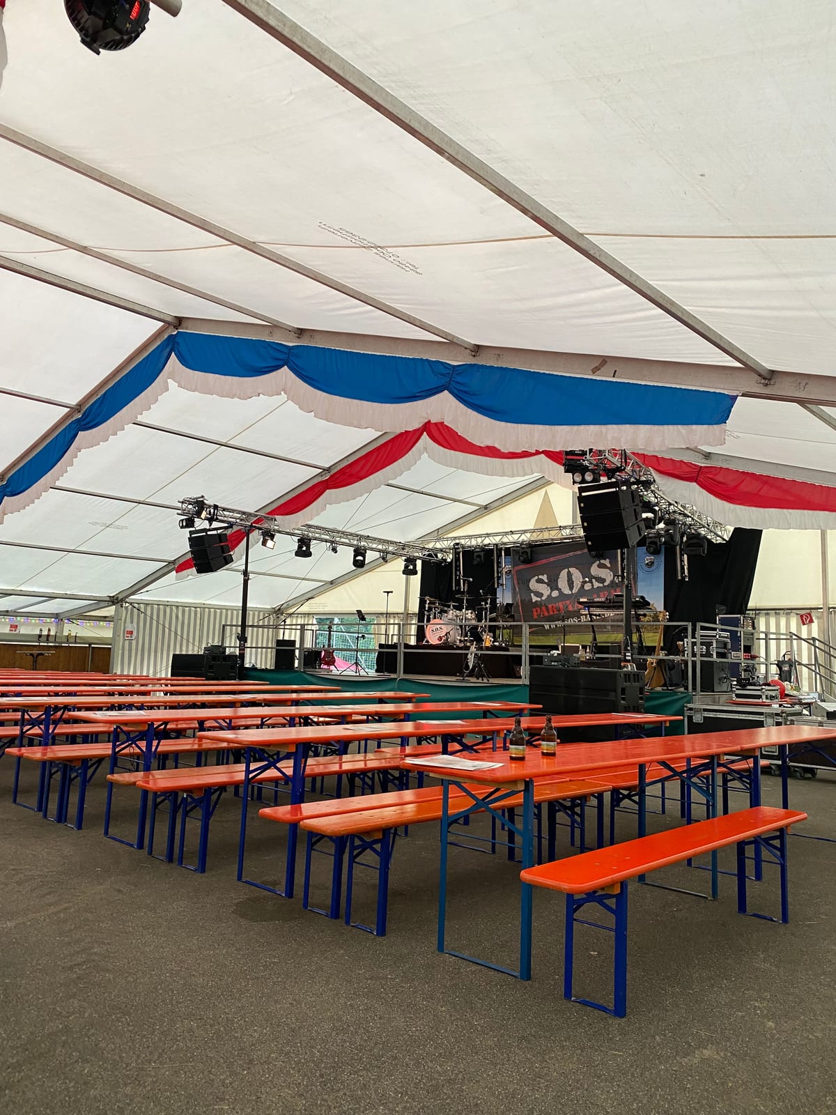 Festzelt mit Bühne, hängender Beschallung und Biergarnituren