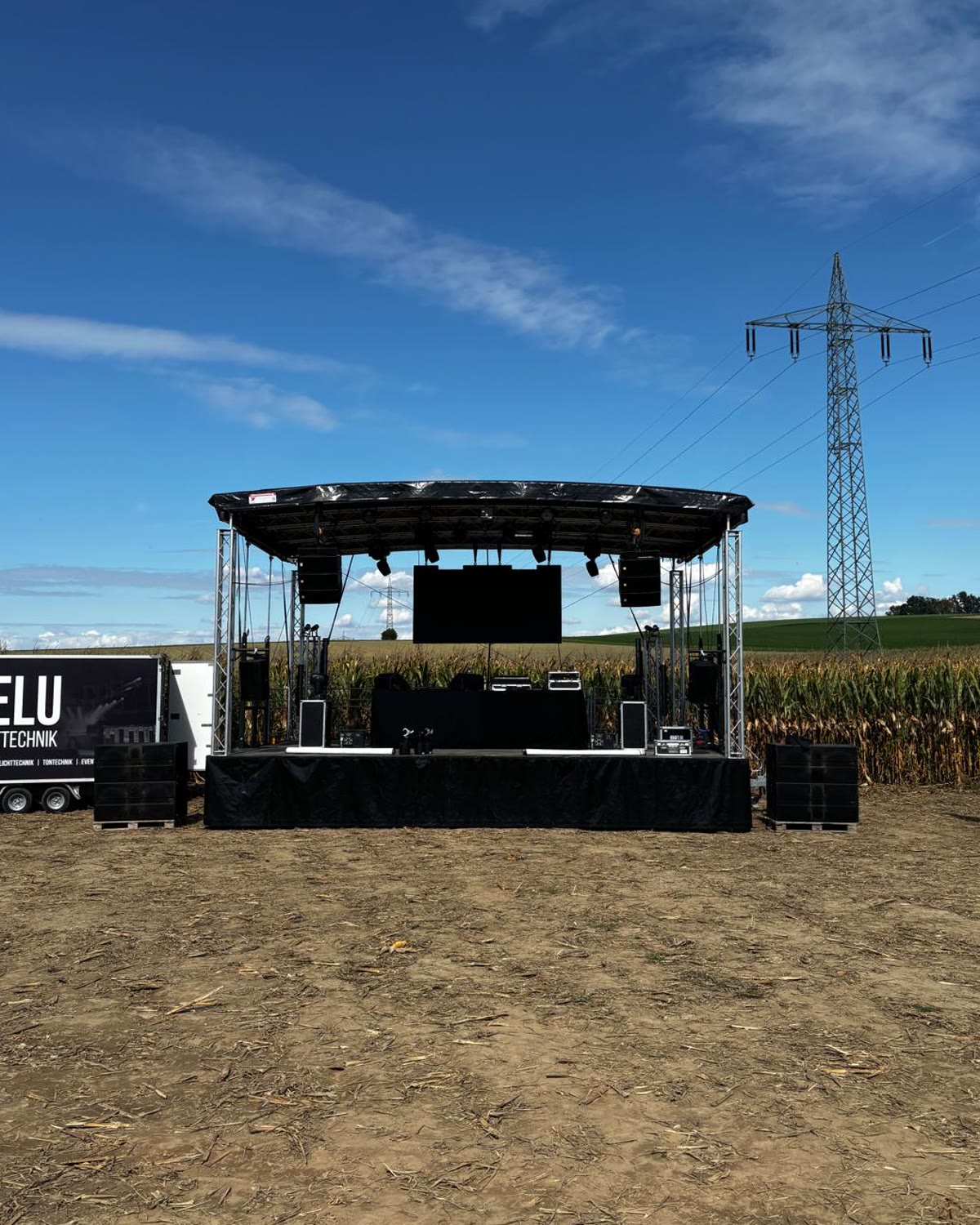 Trailerbühne mit Licht- und Tontechnik vor einem Maisfeld